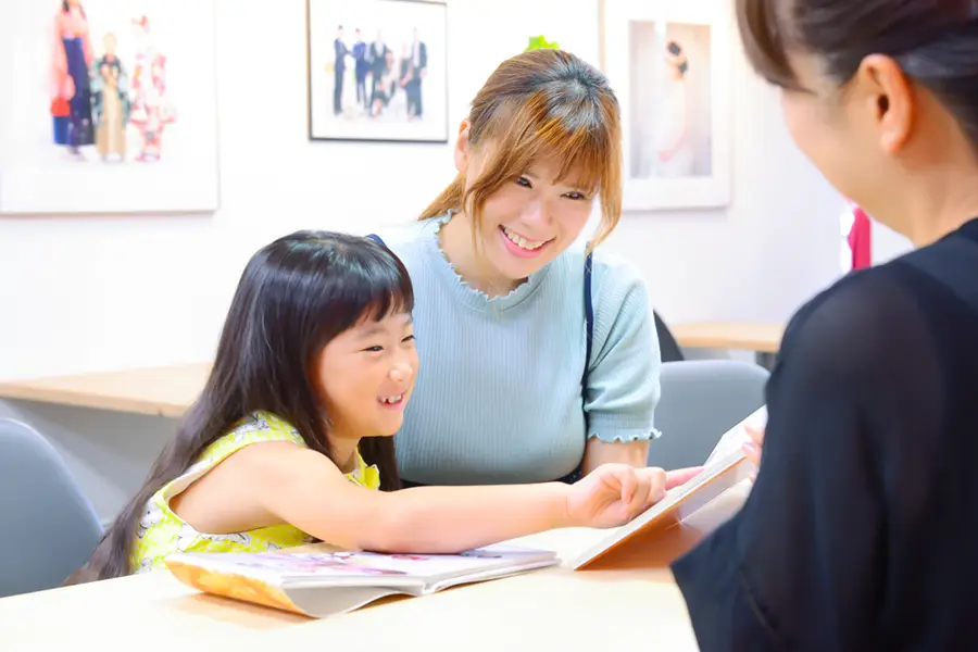 七五三相談会でスタッフとアルバムを見ながら相談する親子